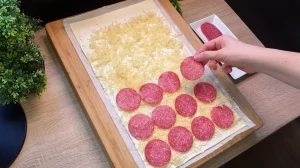 Goldbraun gebackene Salami-Käse-Schnecken aus Blätterteig mit geschmolzenem Käse und grünem Schnittlauch