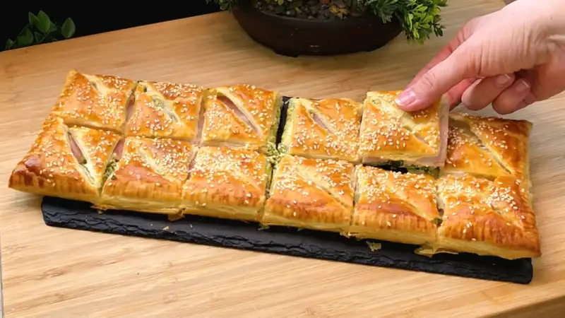 Nahaufnahme eines aufgeschnittenen Blätterteig-Snacks, die cremige Bärlauch-Käse-Füllung zeigt.