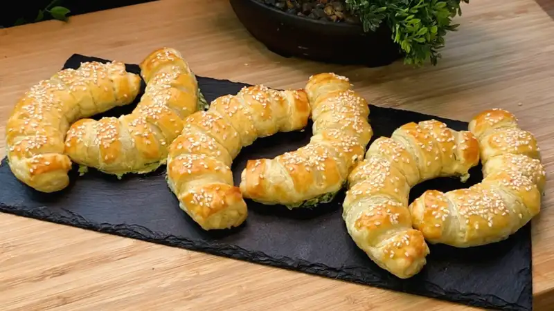 Goldbraun gebackene Bärlauch-Käse-Hörnchen aus Blätterteig mit Sesambestäubung