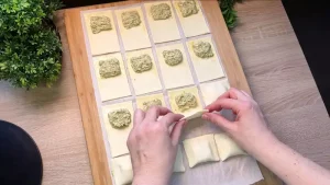 Zubereitungsprozess: Das Falten des Blätterteigs über der cremigen Bärlauchfüllung.