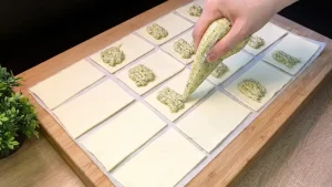 Kleine Blätterteig-Rechtecke werden mit einer grünen Bärlauch-Käse-Creme befüllt.