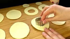 Mit einer ovalen Ausstechform werden Ostereier aus dem frischen Blätterteig ausgestochen.