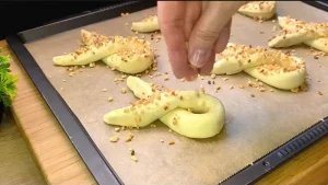 Die fertig geformten Blätterteig-Hasen werden mit Ei bestrichen und mit Nüssen bestreut.