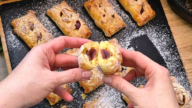 Detailansicht einer aufgeschnittenen Kirsch-Pudding-Tasche mit cremiger Füllung und Mandelsplittern