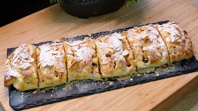 Ein goldbraun gebackener Apfel-Rosinen-Strudel aus Blätterteig mit Mandeln und Puderzucker