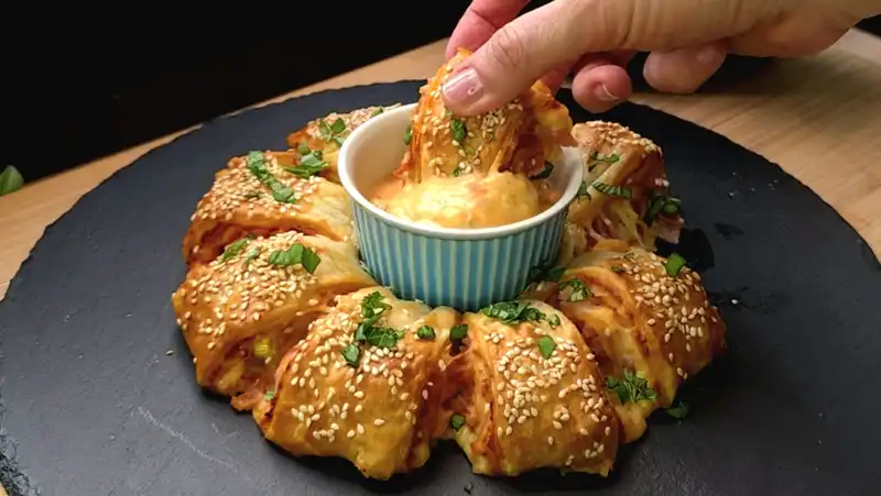 Nahaufnahme eines angeschnittenen Blätterteig-Osterkranzes mit sichtbarer Schinken-Ei-Füllung.