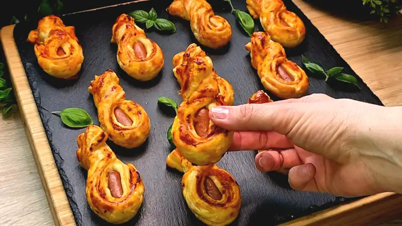 Detailansicht eines gedrehten Blätterteig-Würstchens, das die grüne Pesto-Schicht im Inneren zeigt.