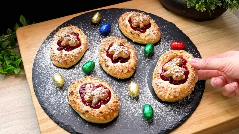 Goldbraun gebackene Oster-Minikuchen aus Blätterteig mit cremiger Quarkfüllung und roter Marmelade