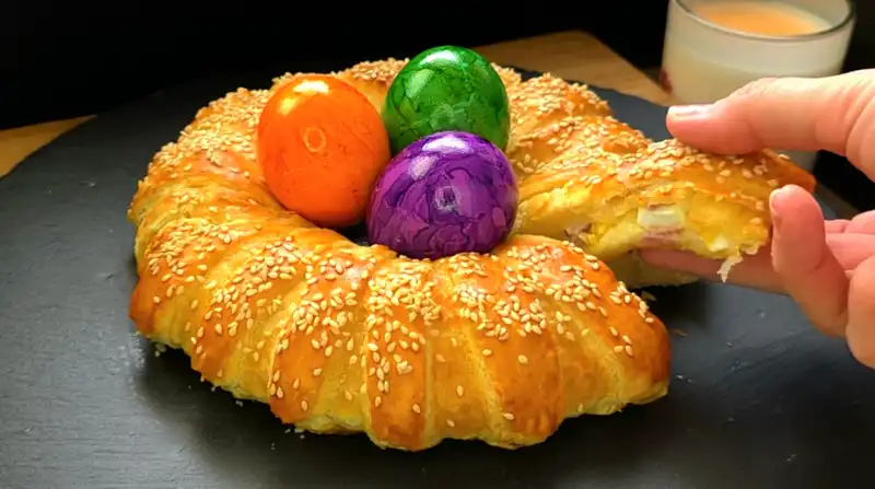 Nahaufnahme eines Anschnitts vom Osterkranz, der die Schinken-Käse-Füllung und das gekochte Ei zeigt.