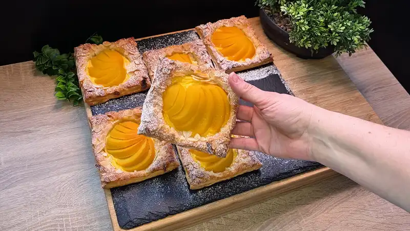 Nahaufnahme eines fertigen Pfirsich-Pudding-Pies mit Puderzucker bestäubt und gerösteten Mandeln.