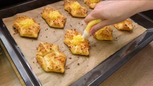 Ein Löffel Vanillepudding wird auf die bereits fertig gebackenen und abgekühlten Blätterteig-Stücke gegeben.