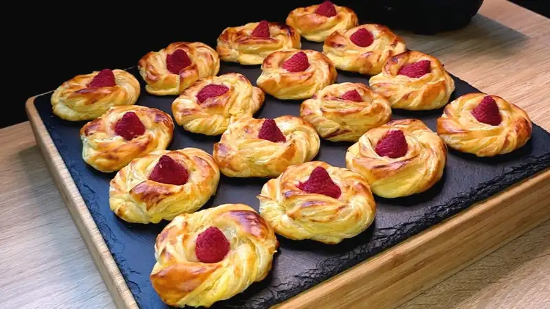 Goldbraun gebackene Blätterteig-Quark-Schnecken mit einer frischen Himbeere in der Mitte.