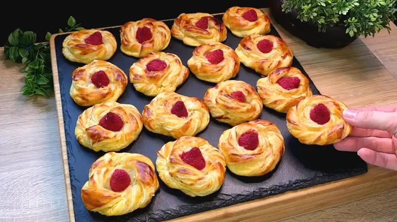 Servierfertige süße Quark-Himbeer-Rollen auf einem Kuchengitter, leicht mit Puderzucker bestäubt.