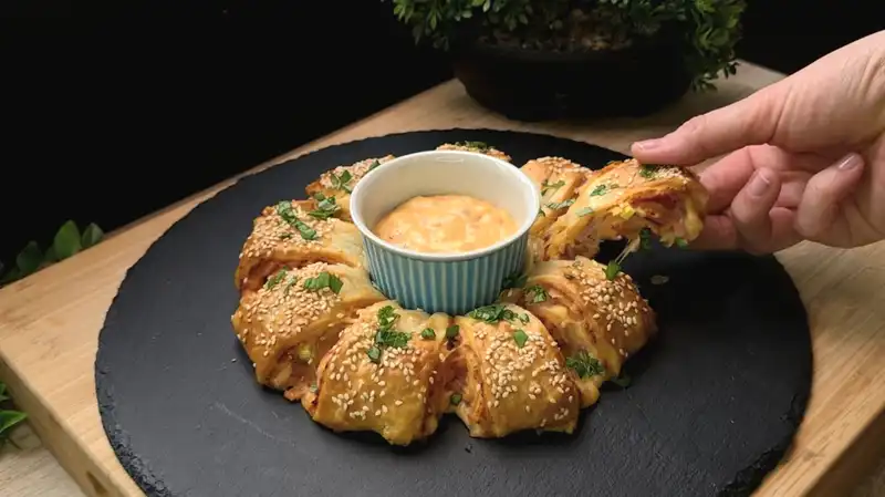 Ein goldbraun gebackener Osterkranz aus Blätterteig, gefüllt mit Schinken, Eiern und Käse.