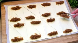 Apfelfüllung wird auf die zugeschnittenen Blätterteig Dreiecke gegeben