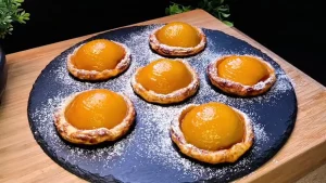 Goldbraun gebackene Blätterteig-Sonnen mit glänzenden Aprikosenhälften und Puderzucker