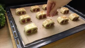 Gefüllte Blätterteig Taschen werden mit Ei bestrichen und mit Walnüssen bestreut auf dem Backblech