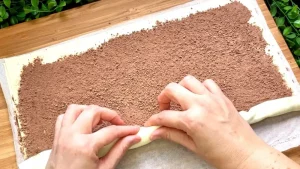 Der Blätterteig wird von beiden Längsseiten zur Mitte hin aufgerollt