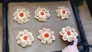 Geformte Blätterteig Würstchen Blumen werden vor dem Bestreichen mit Ei auf ein Backblech gelegt