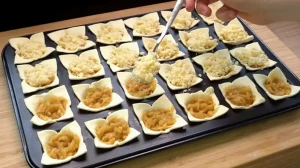 Butterstreusel werden über die Äpfel in den Blätterteig-Förmchen gestreut