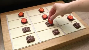 Frische Erdbeerscheiben werden auf Nutella-Kleckse auf dem Blätterteig platziert