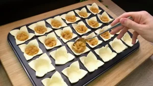 Gedünstete Apfelraspel werden in kleine Blätterteig-Körbchen in der Muffin-Form gefüllt