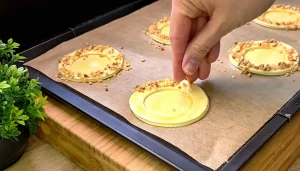 Gehackte Haselnüsse werden auf den mit Ei bestrichenen Blätterteigrand gestreut