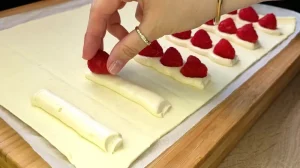 Frische Himbeeren werden auf sechs Streifen Quark-Vanille-Creme auf dem Blätterteig platziert