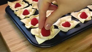 Frische Himbeeren werden in die cremige Füllung in der Form gedrückt