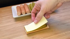 Halbierte Würstchen werden mit Käsescheiben belegt