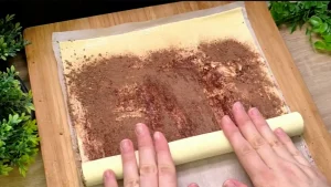 Kakaopulver wird auf die mit Butter bestrichene Blätterteigplatte gesiebt