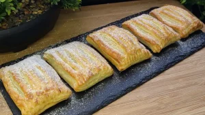 Goldbraun gebackene Blätterteigtaschen mit Marmeladenfüllung und Puderzucker bestäubt