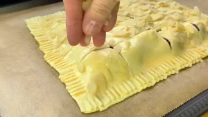 Gehobelte Mandeln werden auf den mit Ei bestrichenen und eingeschnittenen Teig gestreut