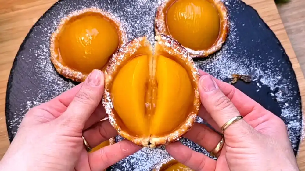 Detailansicht einer Pfirsichhälfte in knusprigem Blätterteig, glasiert mit Aprikosenkonfitüre