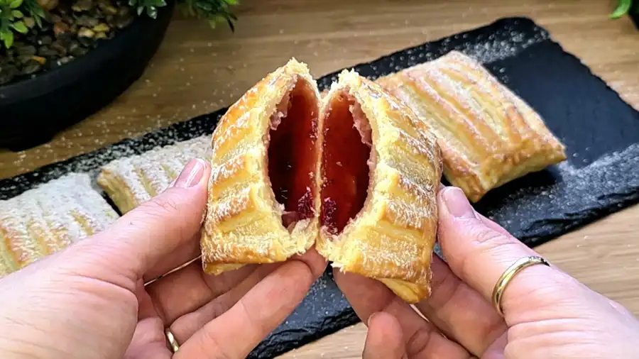 Detailansicht der glänzenden Marmeladenfüllung in einer aufgeschnittenen Blätterteigtasche