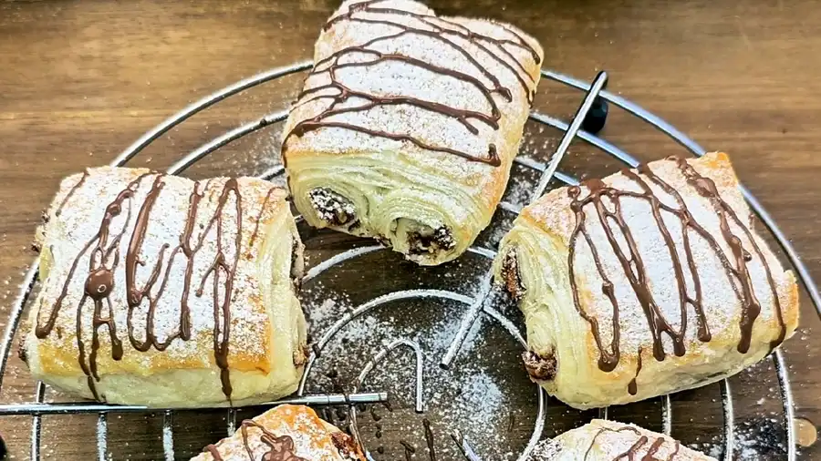 Nahaufnahme einer aufgeschnittenen Blätterteig-Rolle mit flüssiger Kinder Schokolade