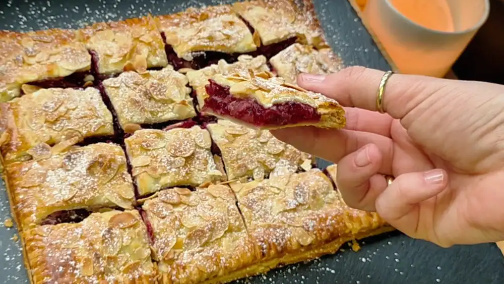 Nahaufnahme des Anschnitts mit der glänzenden Kirschfüllung und dem krossen Teig