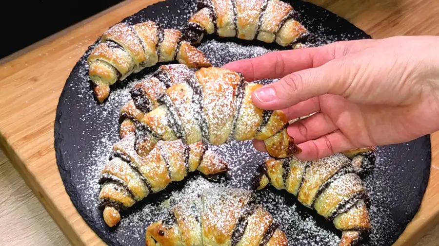 Detailansicht der saftigen Mohnfüllung im Inneren eines knusprigen Blätterteig-Hörnchens