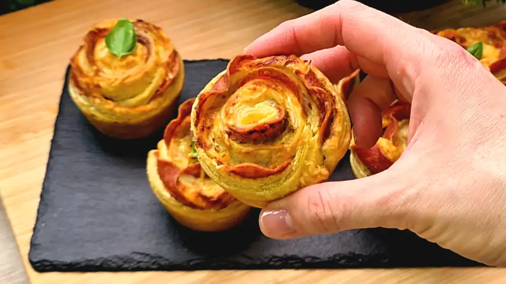 Detailansicht der Schichten aus Salami, grünem Pesto und geschmolzenem Käse in einer Teigrose