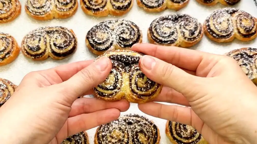 Nahaufnahme der feinen Blätterteigschichten und der dunklen Kakaofüllung