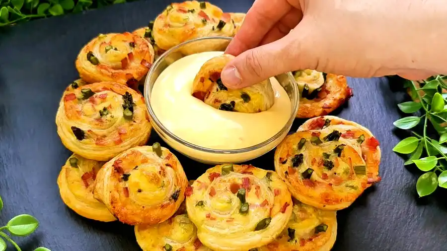 Detailansicht der saftigen Schichten einer Blätterteigschnecke mit geschmolzenem Käse und Spargel