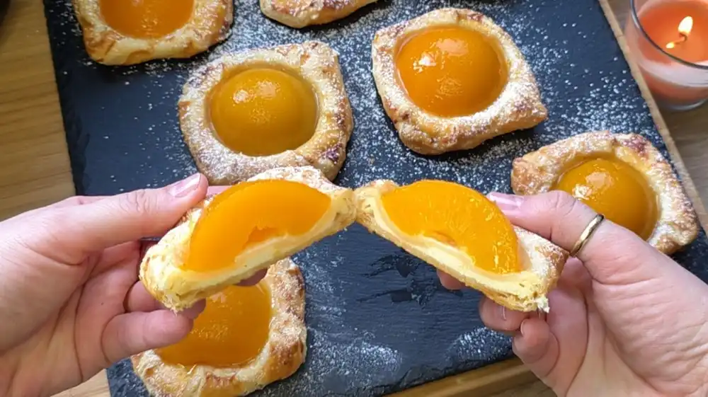 Nahaufnahme von Blätterteig Plunder mit cremiger Quarkfüllung und glänzenden Pfirsichen