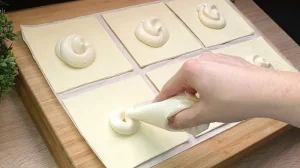 Die weiße Vanille-Quark-Creme wird in die Mitte der Blätterteig-Quadrate gegeben
