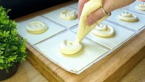 Cremige Quarkfüllung wird auf Blätterteigstücke gestrichen