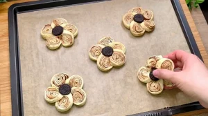 Geformte, ungebackene Blätterteig-Blumen auf einem Backblech mit Backpapier