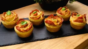 Goldbraun gebackene Salami-Käse-Rosen aus Blätterteig in einer Muffinform