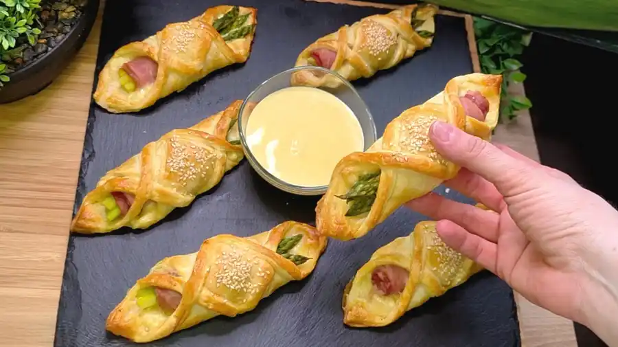 Goldbraun gebackene Blätterteig-Taschen gefüllt mit grünem Spargel, Schinken und Käse