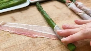 Grüner Spargel wird mit dünnem Speck umwickelt – Vorbereitung für ein schnelles Blätterteig Rezept