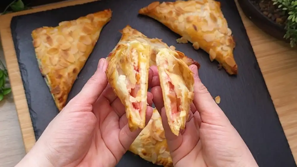 Ein aufgeschnittenes Erdbeer-Quark-Dreieck zeigt die cremige Füllung und die Beeren.
