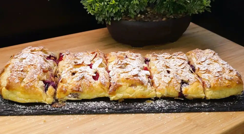 Ein goldbraun gebackener Blätterteig-Strudel mit Beeren, Quark und Mandelblättchen.